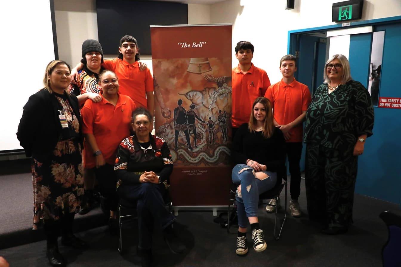 Giinagay staff and community members standing together beside a community banner